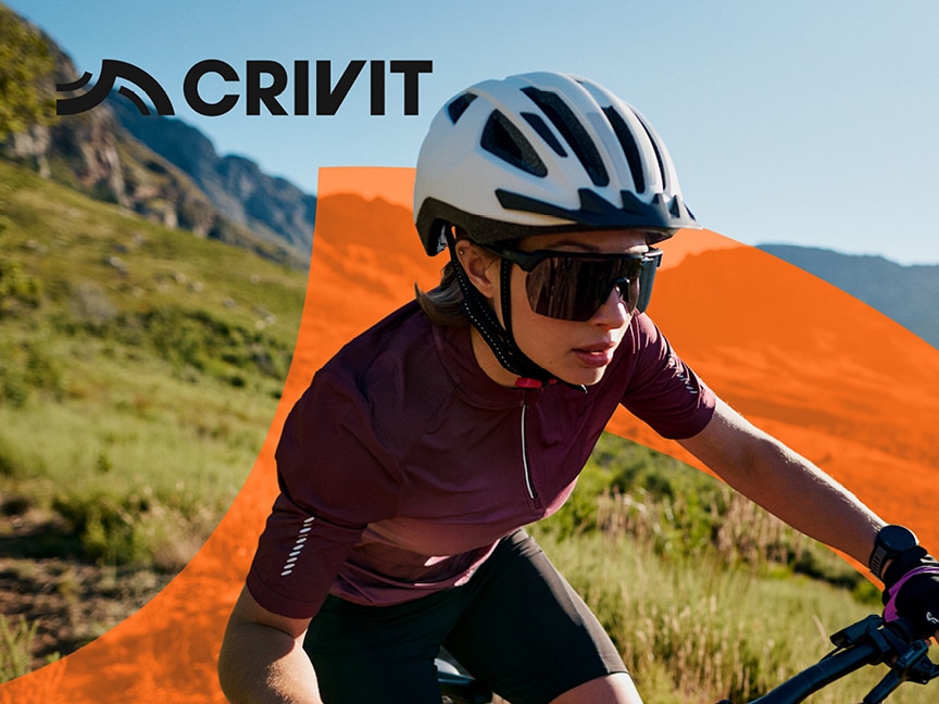 Cyklistka v helmě Crivit jede na horském kole po venkovské cestě.